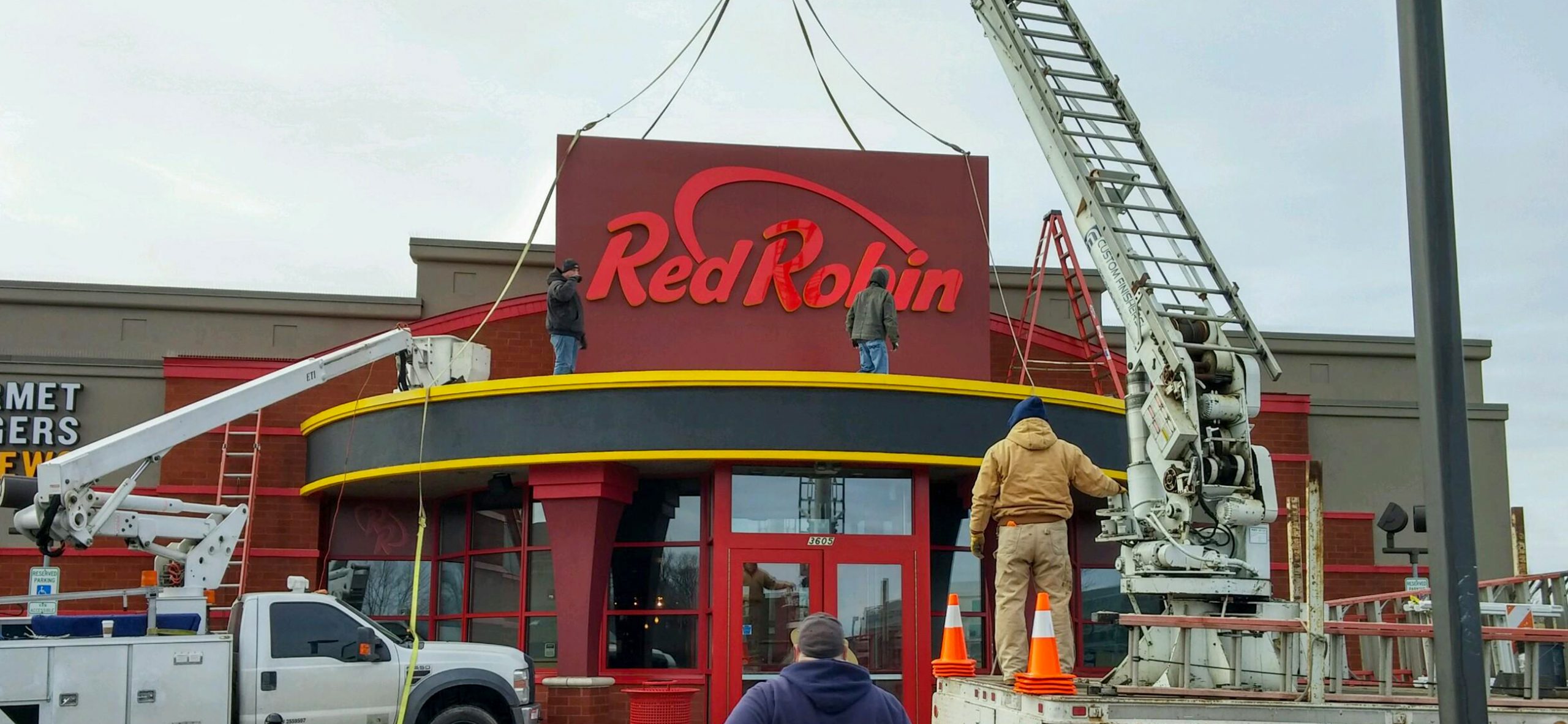 Workers placing a sign at a restaurant entrance.